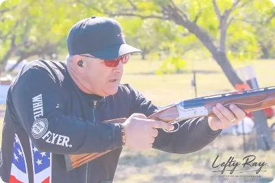 Sporting clays shooter aiming a shotgun outdoors.